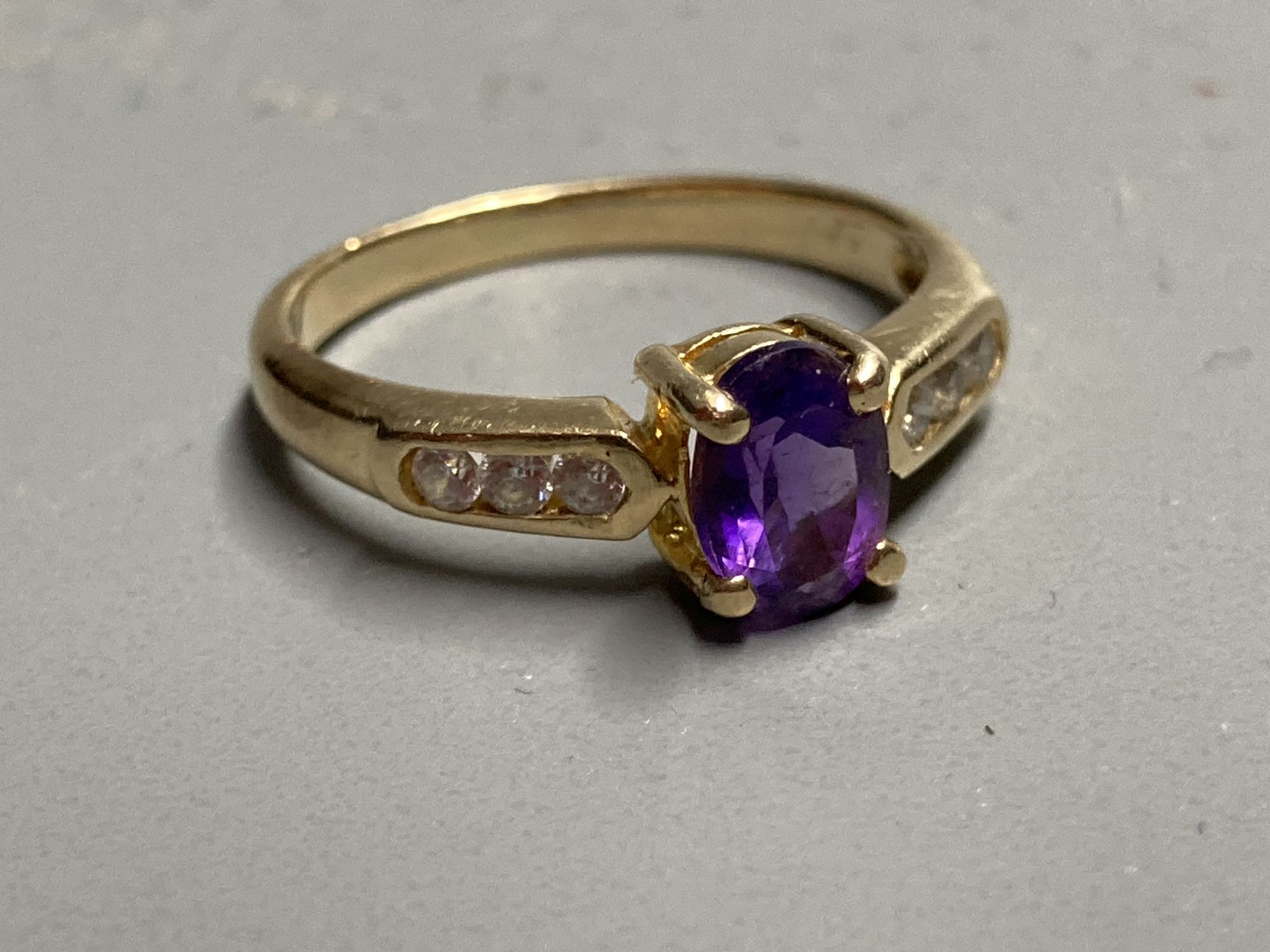 A modern yellow metal, amethyst ring with white stone (possibly white sapphire) set shoulders, size L, gross 2.7 grams.